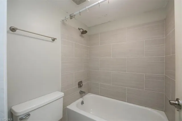 a white bath tub sitting next to a white toilet and a shower