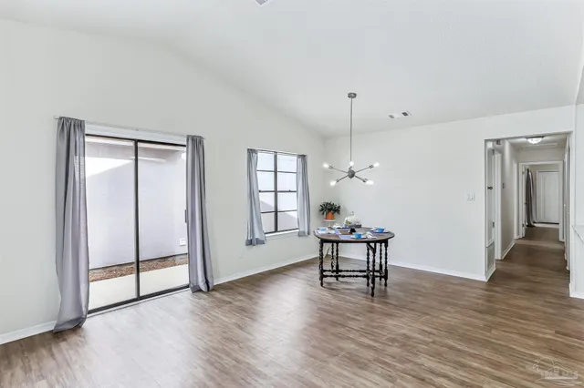 an empty room with wooden floor chandelier fan and windows