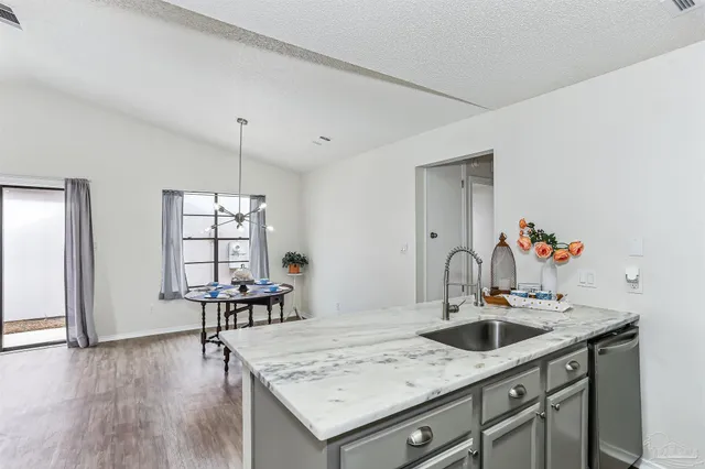 a view of kitchen island with sink refrigerator dining table and chairs