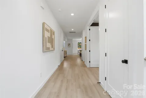 a room with chandelier fan and a wooden floor