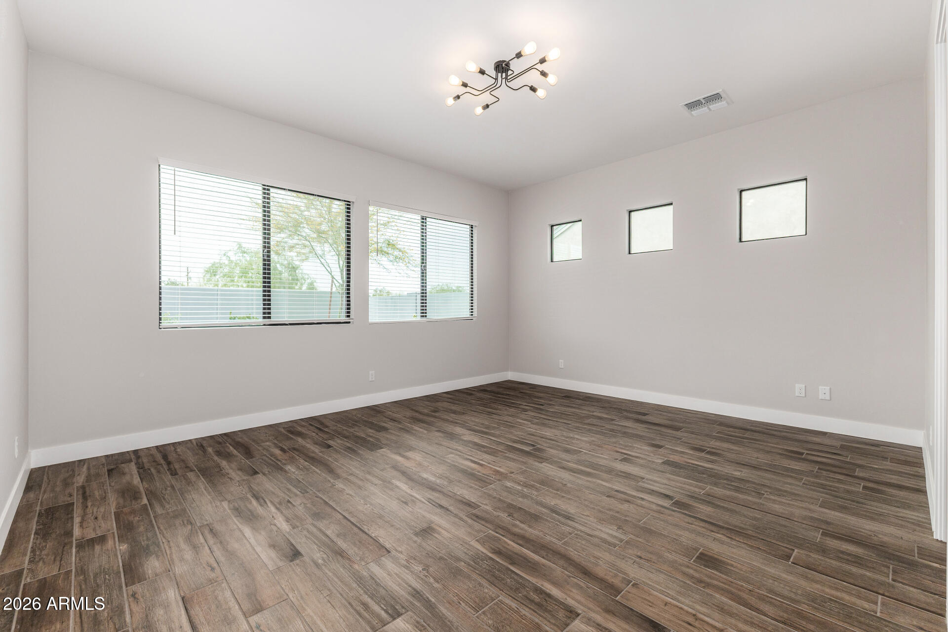 9818 South 7th Place Phoenix, AZ 85042 - Photo 20 of 62 a view of an empty room with wooden floor and a window