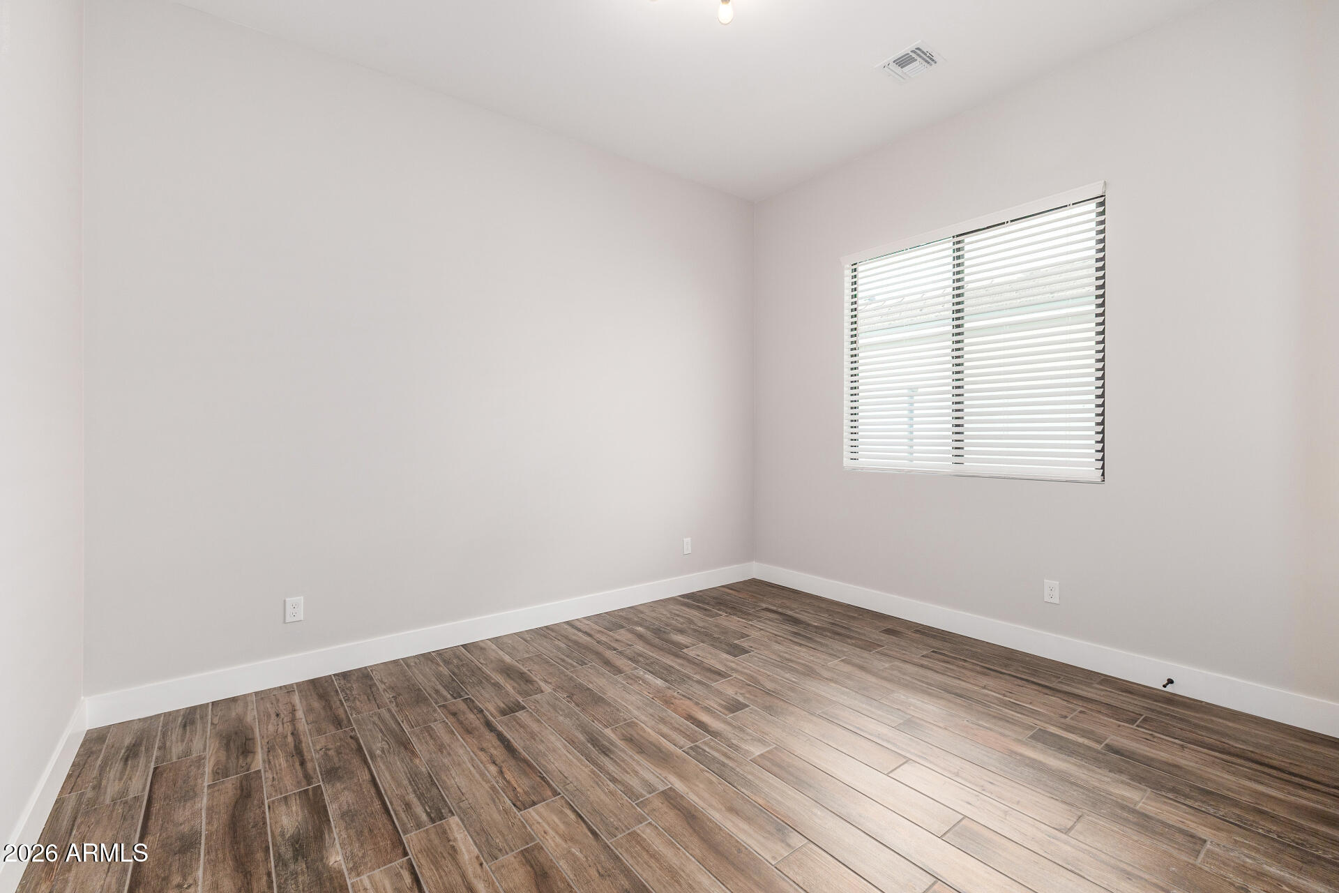 9818 South 7th Place Phoenix, AZ 85042 - Photo 26 of 62 an empty room with wooden floor and windows