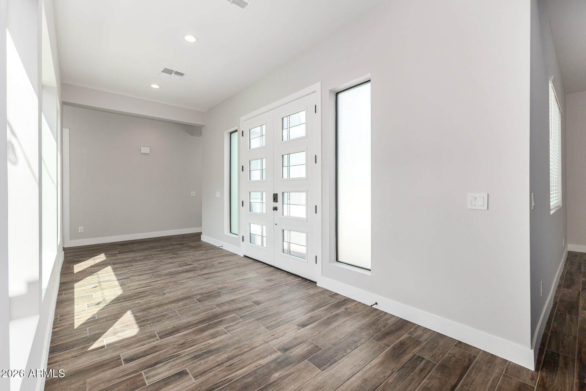 9818 South 7th Place Phoenix, AZ 85042 - Photo 6 of 62 a view of an empty room with wooden floor and a window