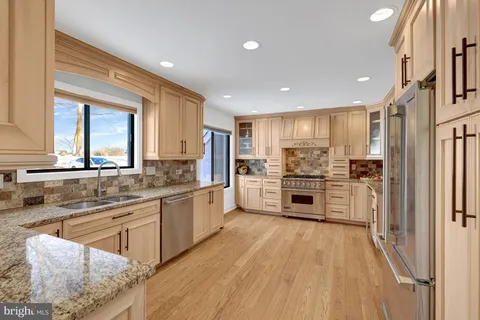 a kitchen with stainless steel appliances granite countertop a refrigerator oven a sink dishwasher and white cabinets with wooden floor