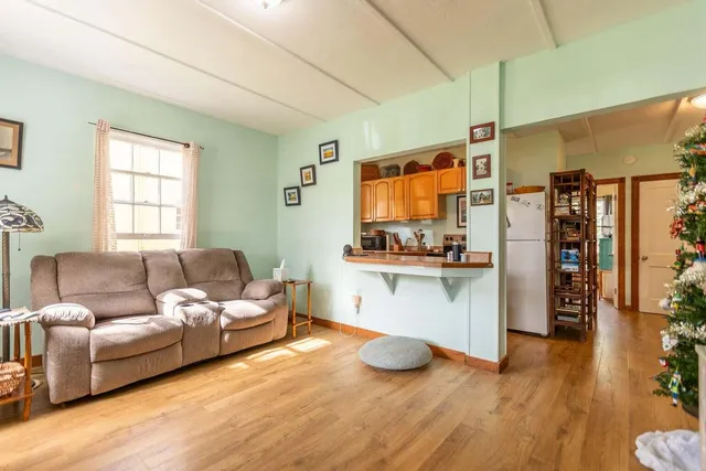a living room with stainless steel appliances kitchen island granite countertop furniture and a wooden floor