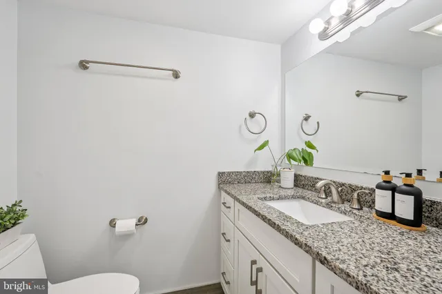 a bathroom with a granite countertop sink a mirror and a toilet