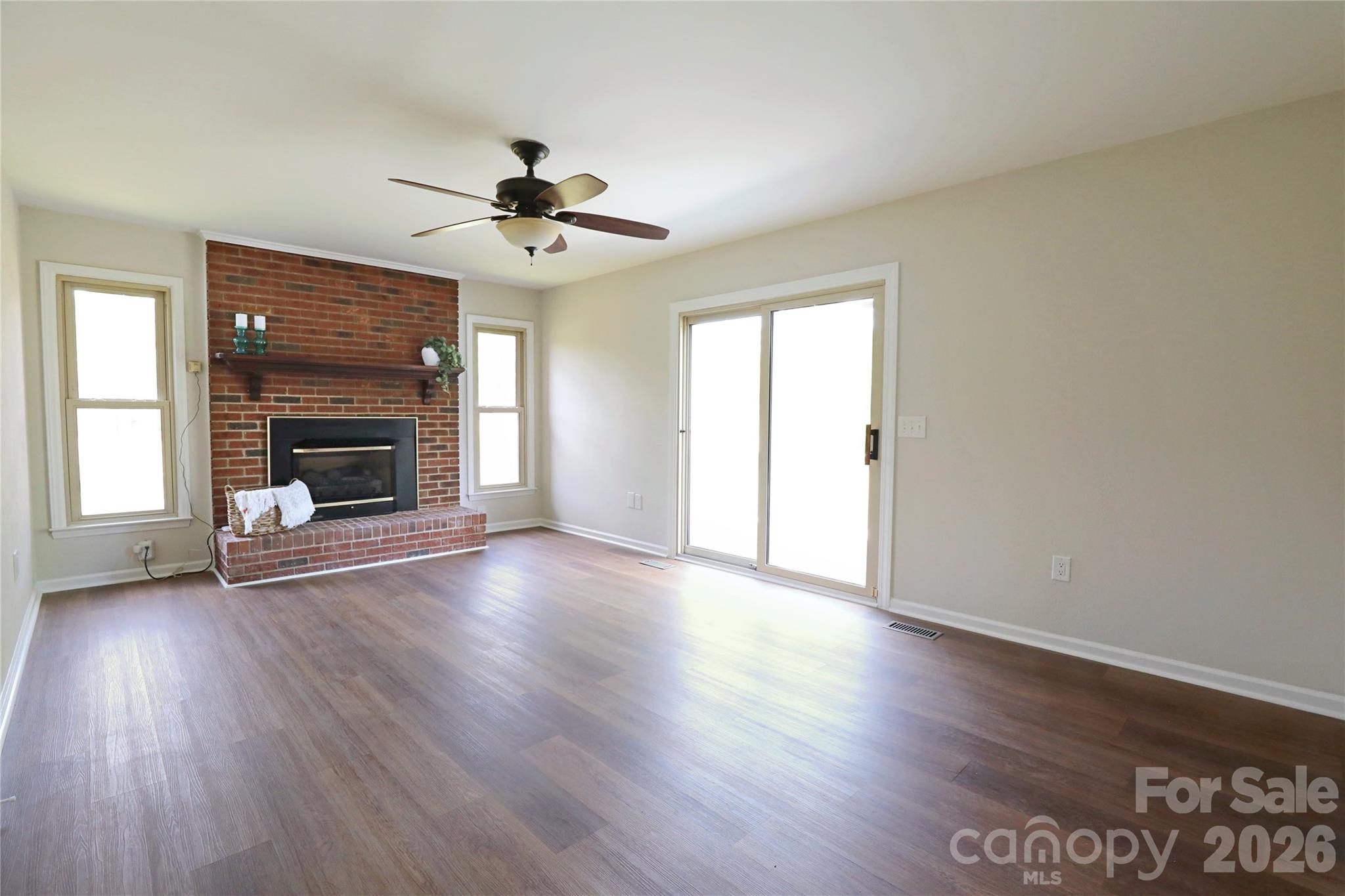 12809 Pine Bluff Road Midland, NC 28107 - Photo 13 of 41 an empty room with wooden floor fireplace fan and windows