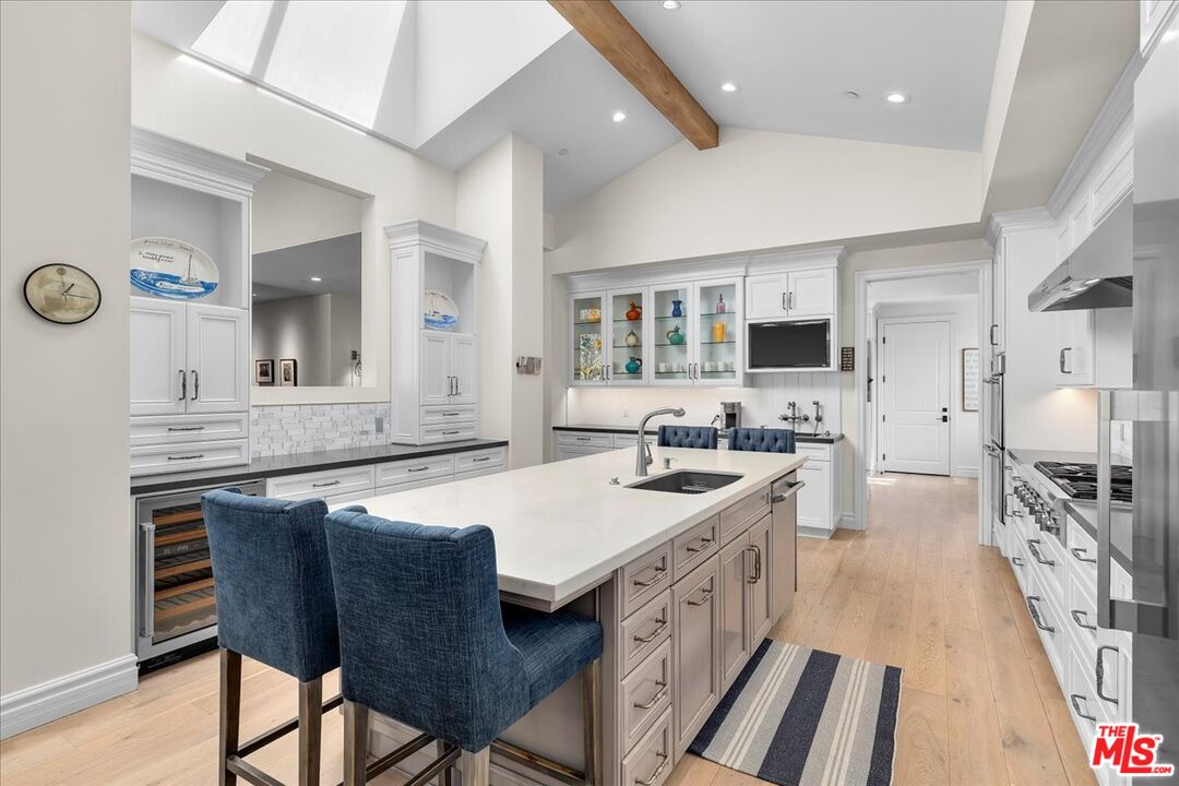 809 Leonard Road Los Angeles, CA 90049 - Photo 26 of 72 a kitchen with stainless steel appliances granite countertop a stove top oven a sink dishwasher a dining table and chairs with wooden floor