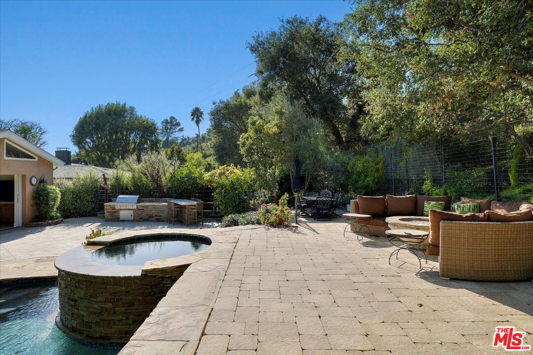 809 Leonard Road Los Angeles, CA 90049 - Photo 61 of 72 a view of a patio with couches and chairs under an umbrella with large trees