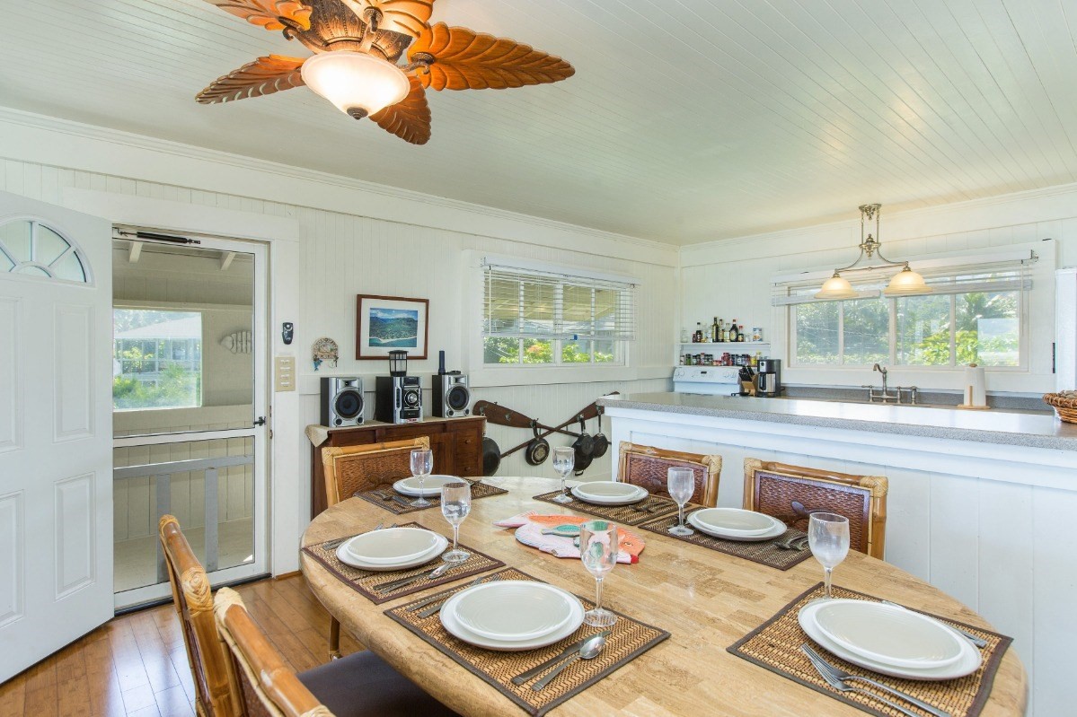7206 Alamoo Road Hanalei, HI 96714 - Photo 7 of 17 a dining room with furniture a kitchen wooden floor and a chandelier