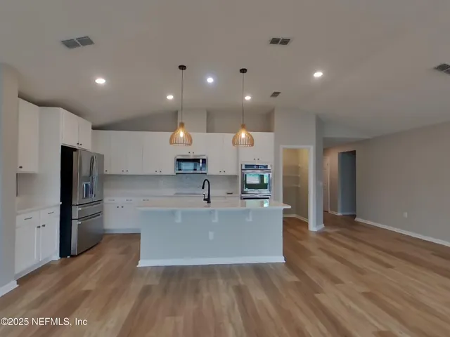 a large kitchen with stainless steel appliances a large counter top and a wooden floors