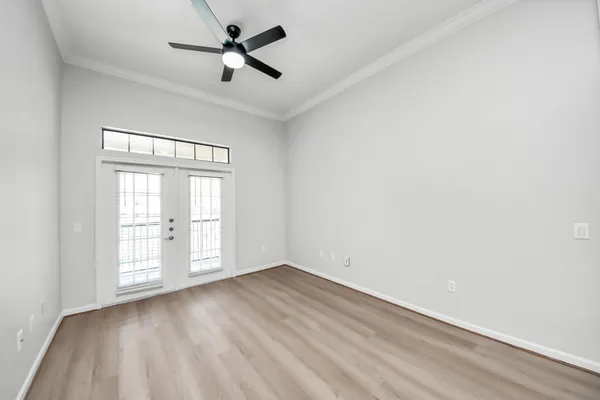 an empty room with wooden floor fan and windows