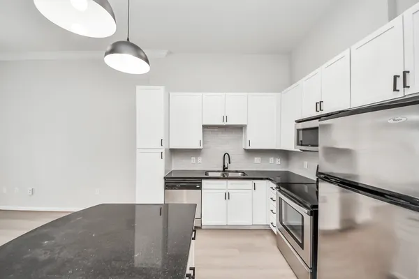 a kitchen with granite countertop a sink a stove and cabinets
