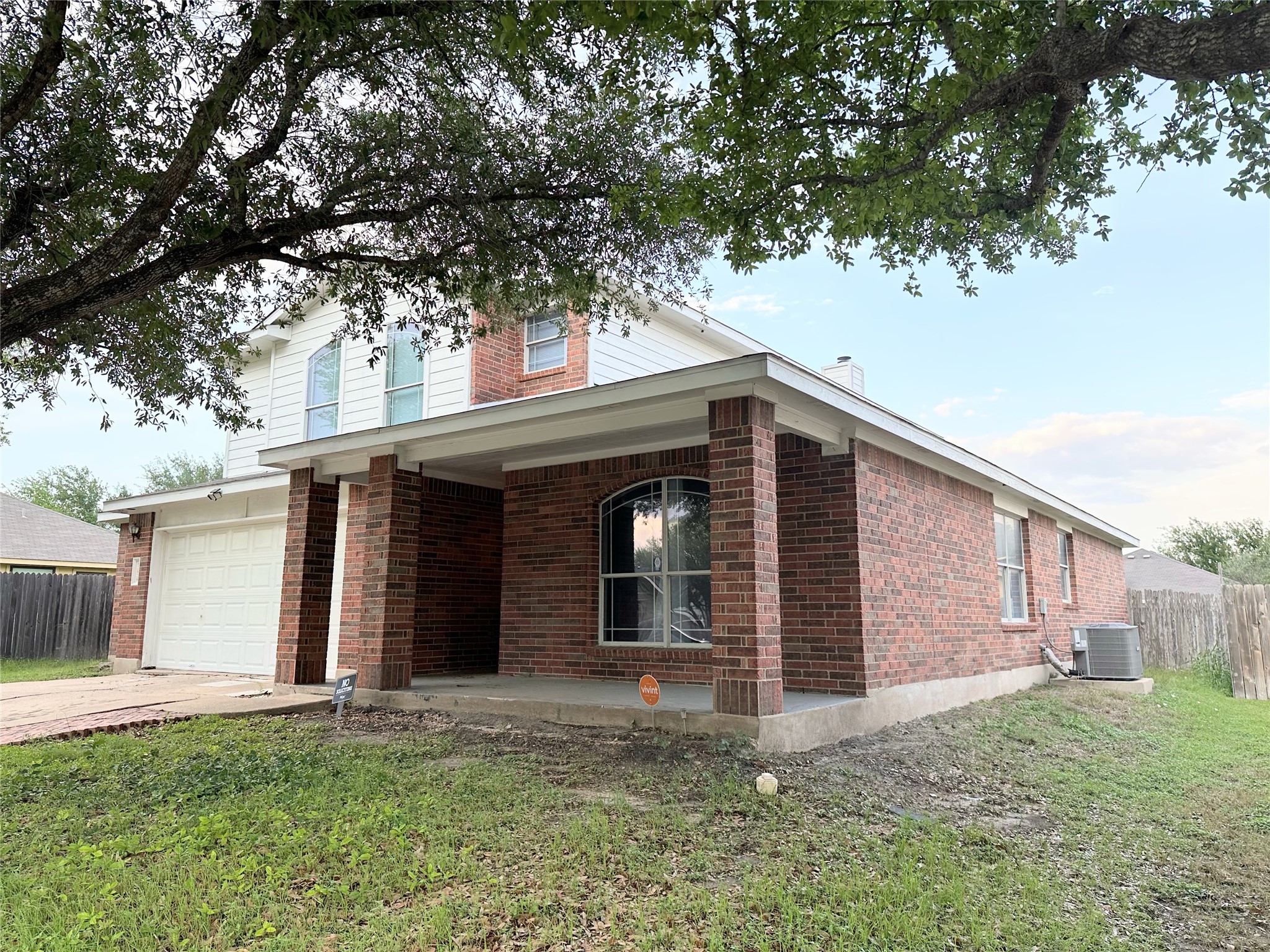 12929 Waynespur Lane Elgin, TX 78621 - Photo 2 of 20 The property features a brick and white siding exterior, a covered front porch, and an attached garage