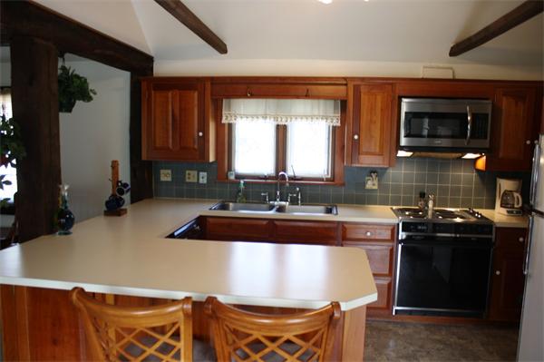 254 Plumtree Road Sunderland, MA 01375 - Photo 5 of 15 a kitchen with kitchen island granite countertop a sink and a stove top oven with wooden cabinets