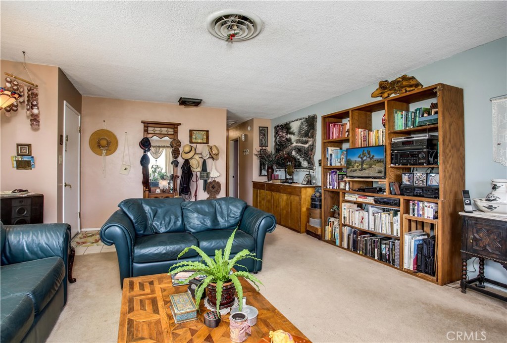 5407 Paradise View Road Yucca Valley, CA 92284 - Photo 12 of 63 a living room with furniture a bookshelf and a window