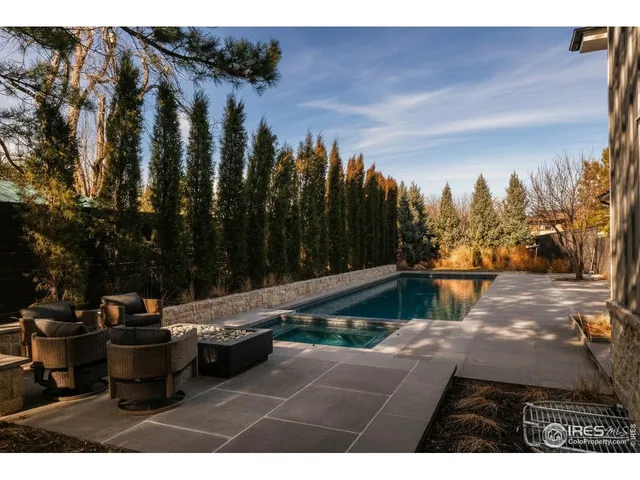 a view of swimming pool outdoor seating and trees in the background