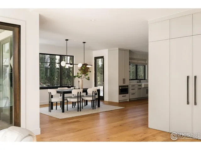 a large white kitchen with stainless steel appliances kitchen island granite countertop a sink dishwasher a stove a dining table with chairs with wooden floor