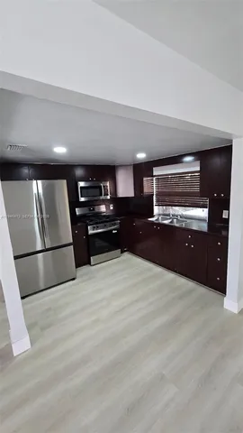 a kitchen with stainless steel appliances kitchen island granite countertop a refrigerator and a sink
