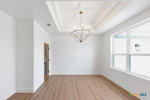 a view of an empty room with wooden floor fireplace and a window