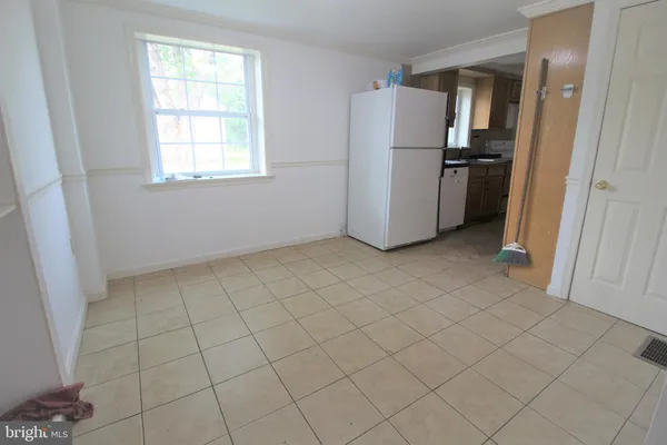 an empty room with a white cabinet and a refrigerator