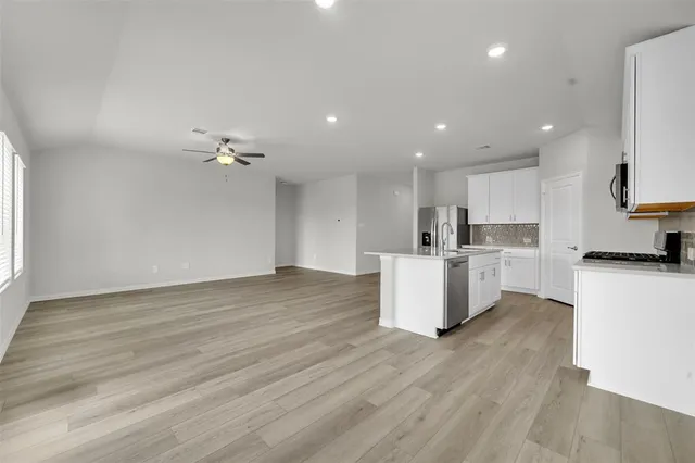 a view of kitchen with kitchen island stainless steel appliances wooden cabinets and window