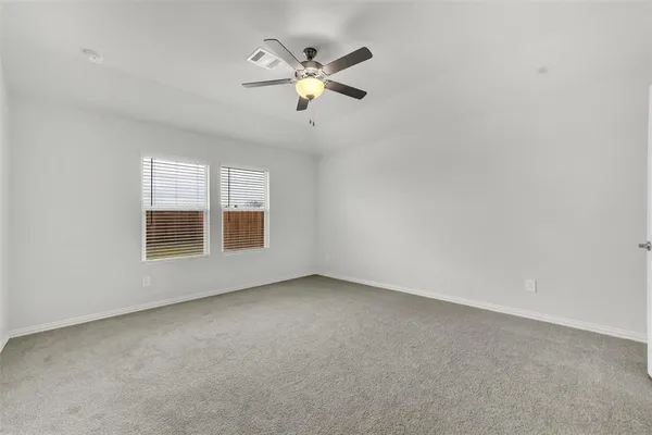 an empty room with ceiling fan and windows