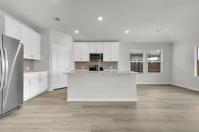 a large white kitchen with a refrigerator a stove top oven and white cabinets