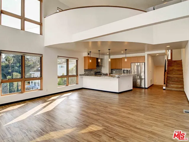 a view of a big room with wooden floor and windows