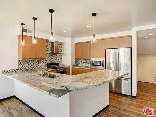 a kitchen with stainless steel appliances granite countertop a sink and a refrigerator