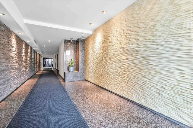 a view of a hallway with wooden floor and a bathroom