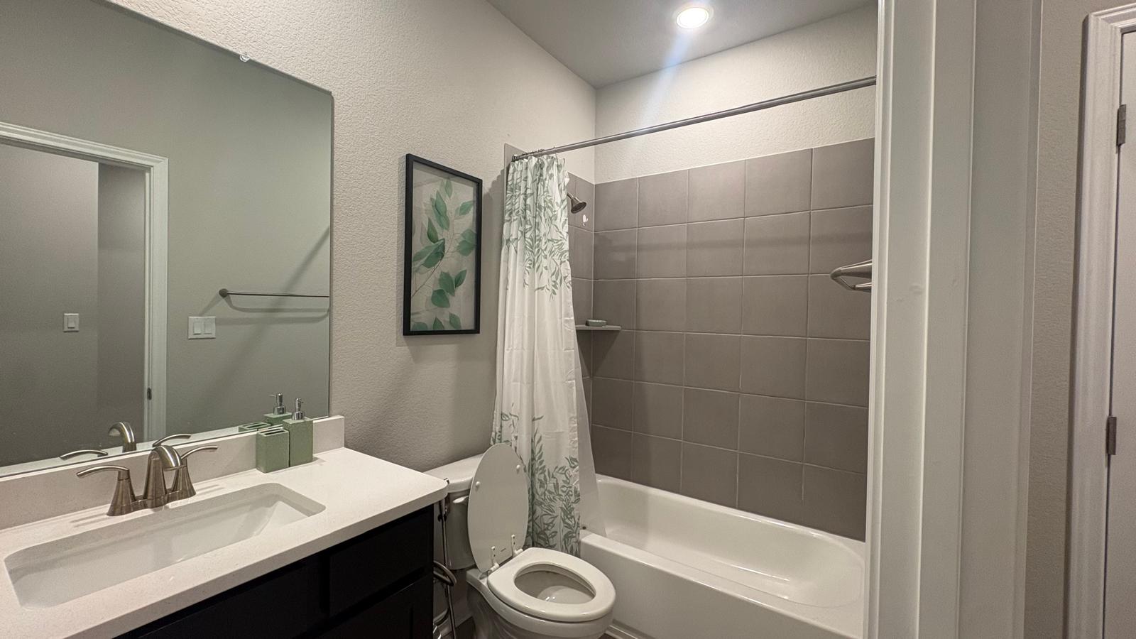6511 Dragride Road Buda, TX 78610 - Photo 20 of 36 A well-appointed bath features a sleek vanity, mirror, and a tiled shower-tub combination.