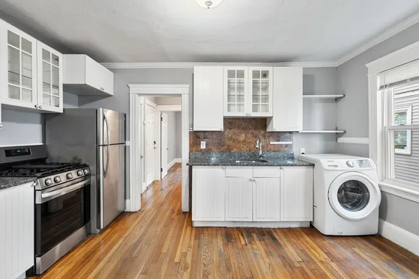a kitchen with granite countertop a refrigerator a stove and wooden floor