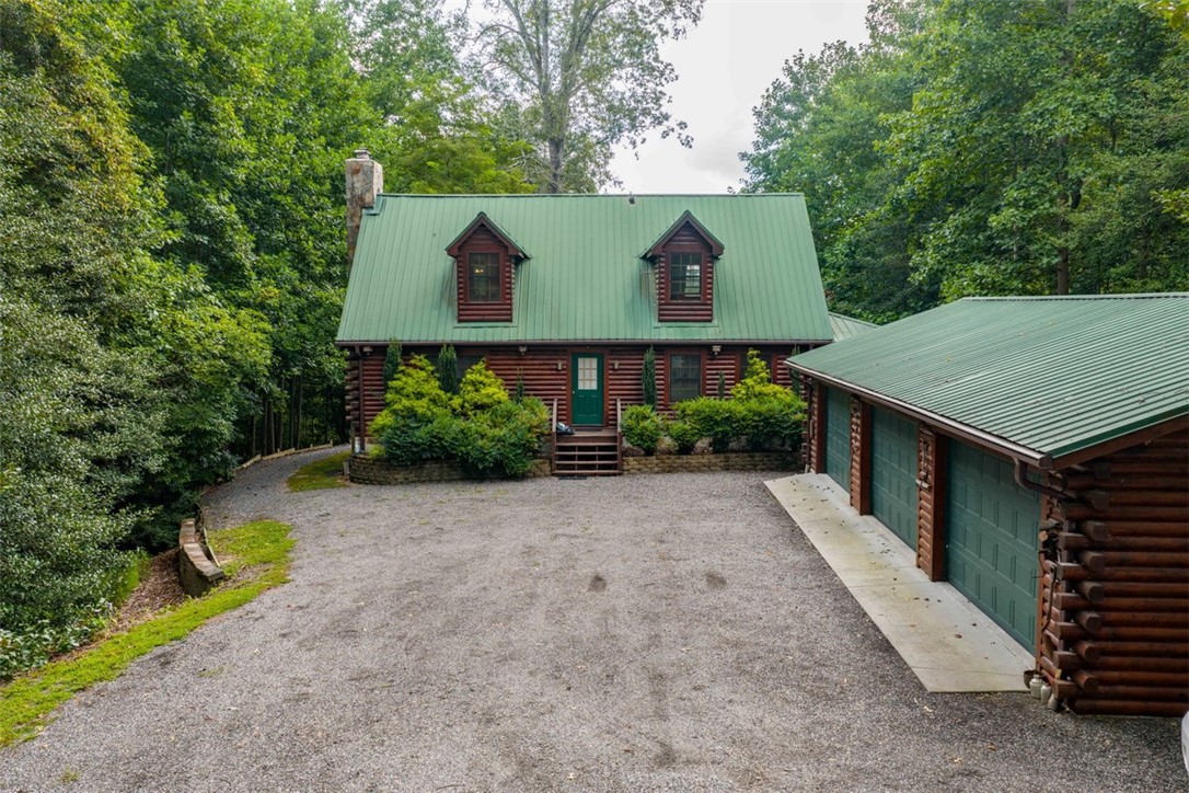 846 Twiggs Ferry Road Hartfield, VA 23071 - Photo 2 of 28 Log-style house featuring log exterior, a chimney, a metal roof, a garage, and an outbuilding