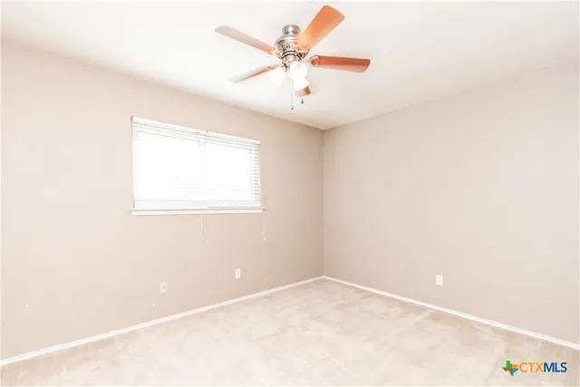 an empty room with a window and a ceiling fan