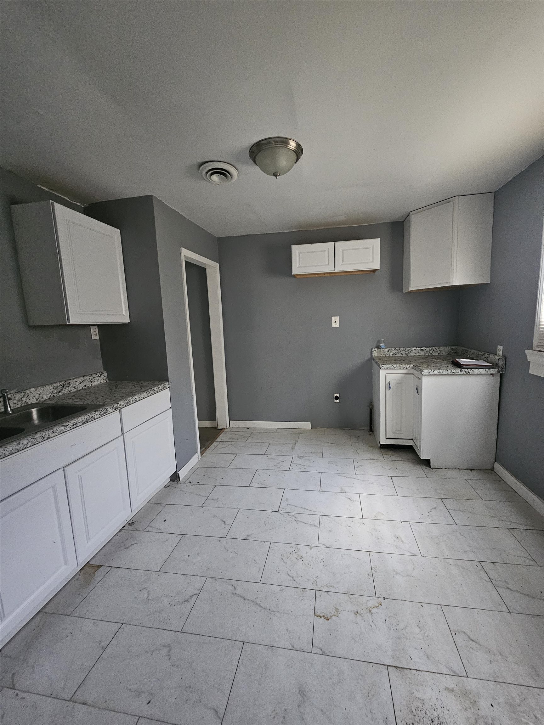 2059 Swift Street Memphis, TN 38109 - Photo 5 of 12 Kitchen featuring white shaker-style cabinetry, light-toned countertops, and a stainless steel sink