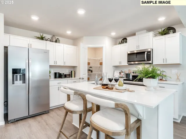 a kitchen with a refrigerator a stove a sink and chairs