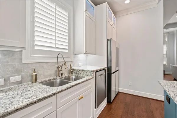 a kitchen with stainless steel appliances granite countertop a sink dishwasher a refrigerator and a stove with wooden floor