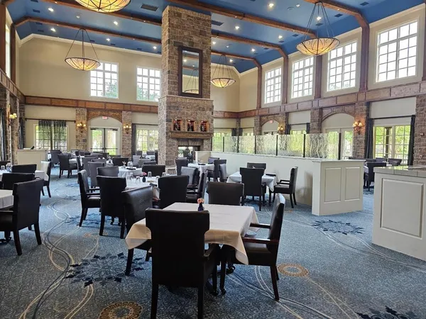 a room with lots of tables a large window and chairs