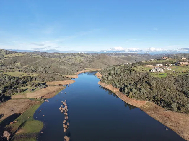 an aerial view of ocean and residential houses with outdoor space