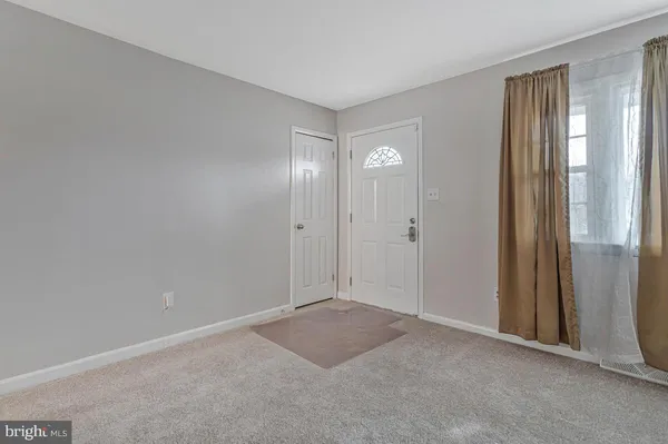 a view of an empty room with window and closet area