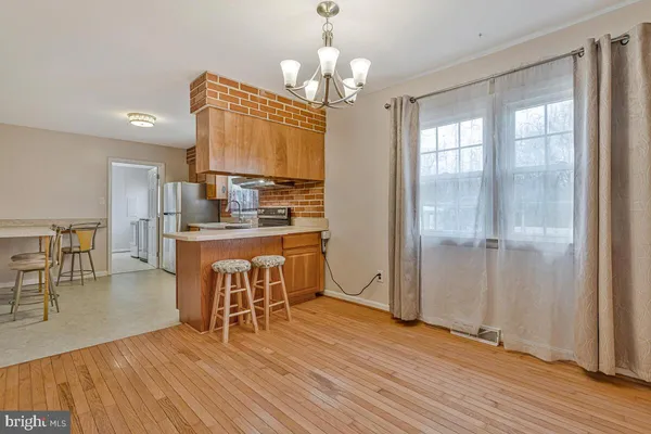 a dining room with wooden floor a chandelier a glass table and chairs