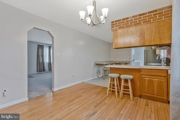 a dining room with wooden floor a chandelier a wooden table and chairs