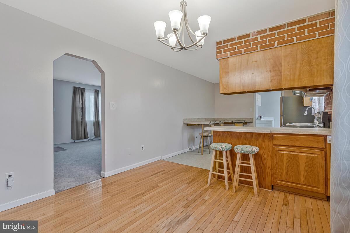 6015 Cracklingtown Road Hughesville, MD 20637 - Photo 4 of 17 a dining room with wooden floor a chandelier a wooden table and chairs