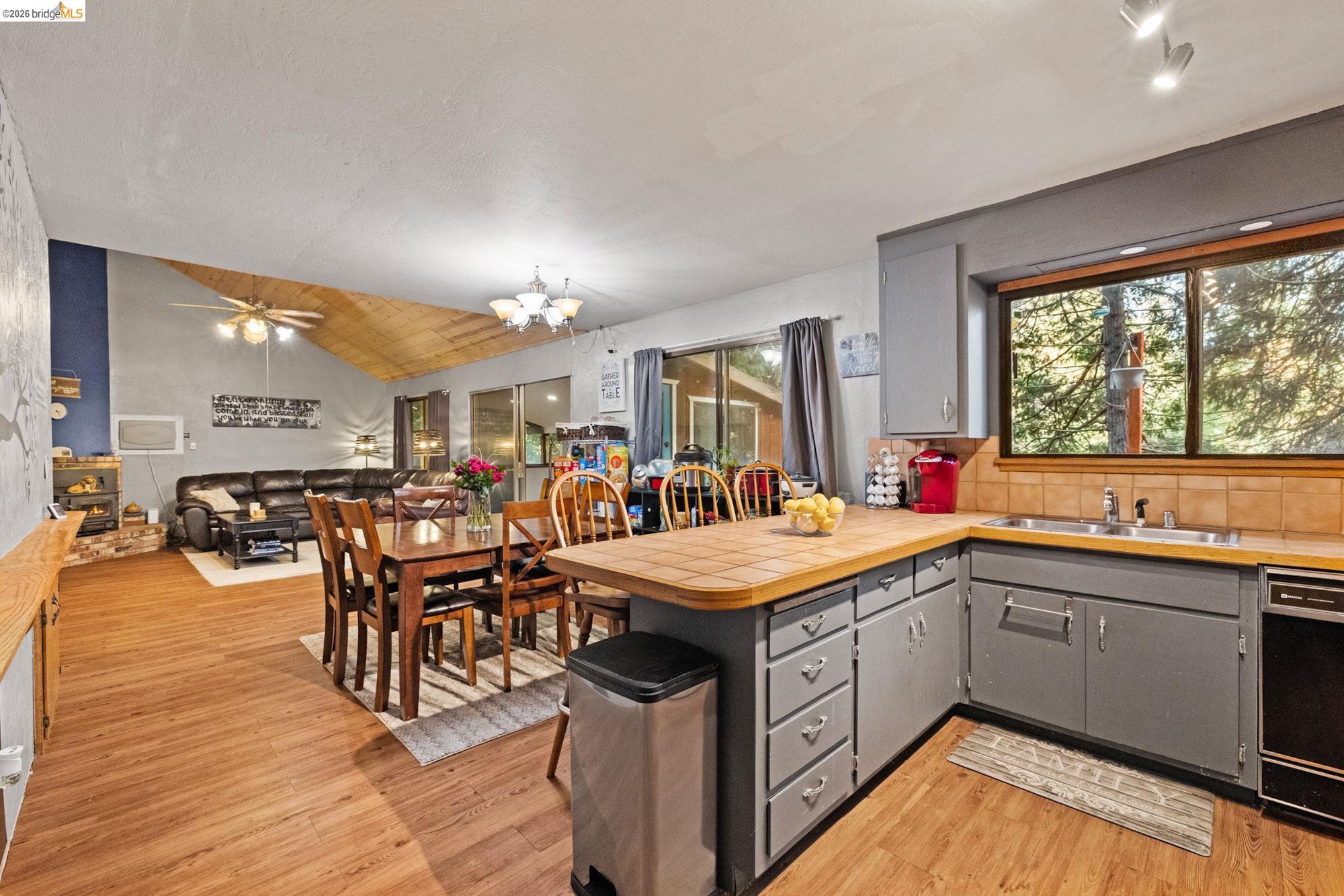 17851 Robin Road Twain Harte, CA 95383 - Photo 11 of 45 Kitchen featuring gray cabinetry, tile counters, a chandelier, vaulted ceiling, and a peninsula