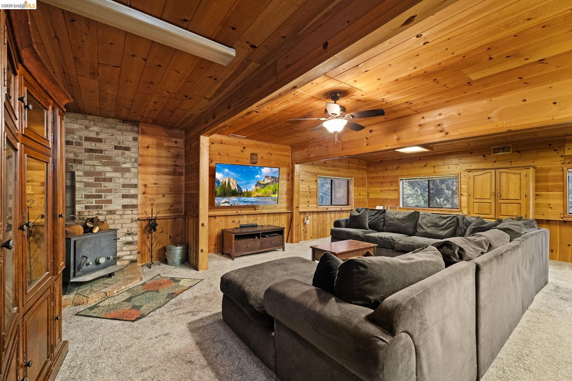 17851 Robin Road Twain Harte, CA 95383 - Photo 27 of 45 Living room featuring wooden walls, carpet flooring, wood ceiling, and a ceiling fan