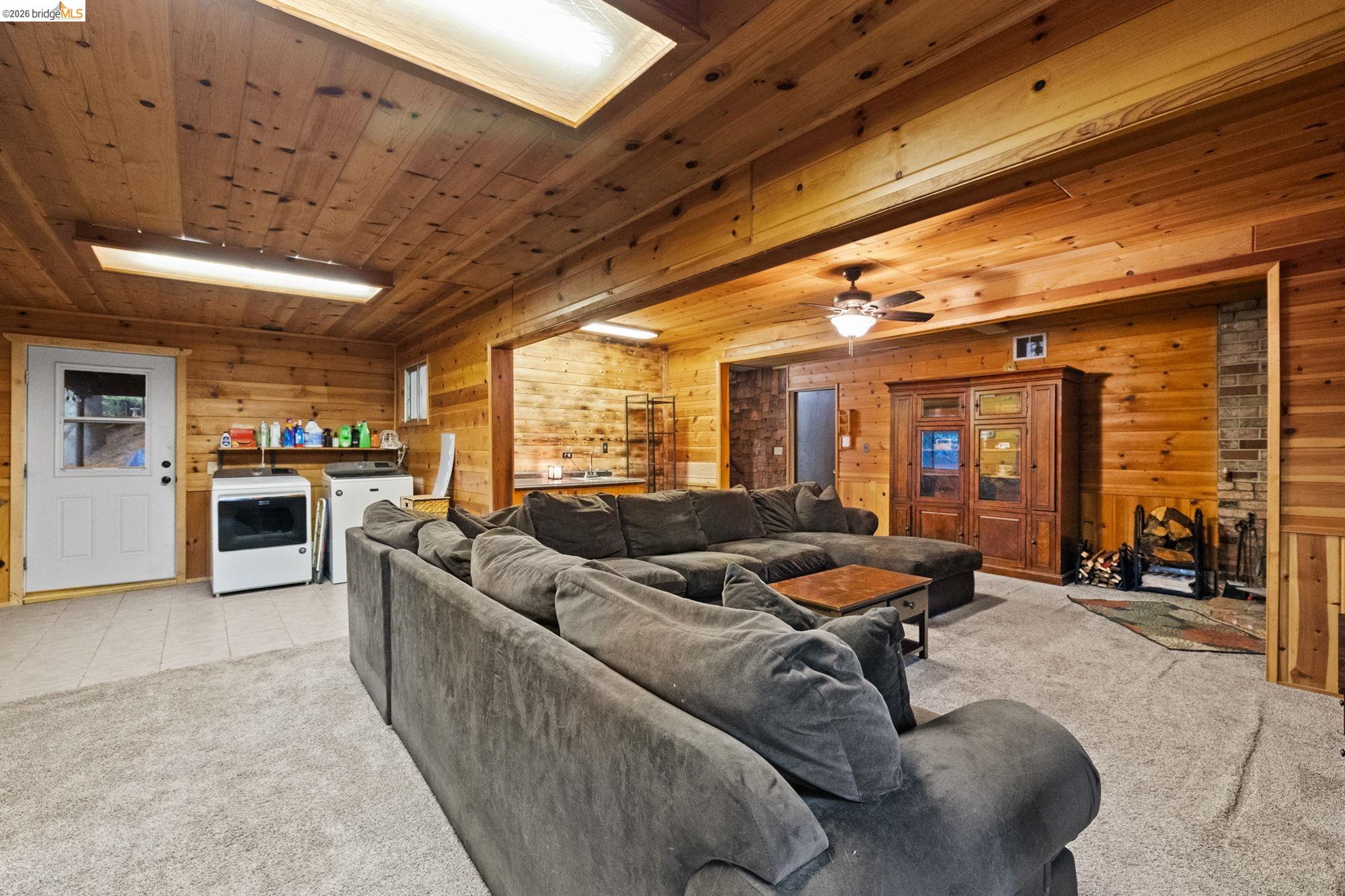 17851 Robin Road Twain Harte, CA 95383 - Photo 31 of 45 Living room with light carpet, wood walls, washer and clothes dryer, wooden ceiling, and ceiling fan
