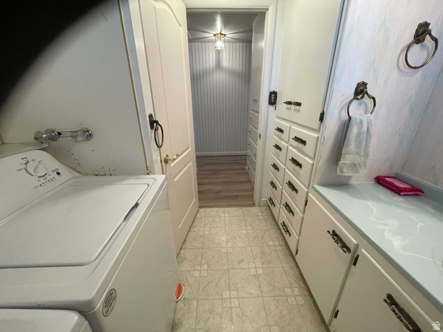 438 East Main Street Elsinore, UT 84724 - Photo 18 of 43 Compact laundry and half bath, featuring a tile floor, white cabinetry, a light blue countertop, and a hallway beyond with wood-finish flooring