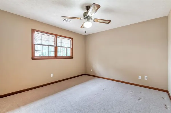 an empty room with a ceiling fan and window