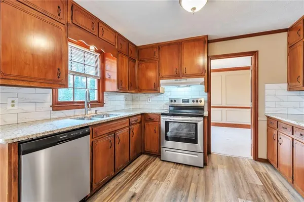 a kitchen with stainless steel appliances granite countertop a stove a sink and a refrigerator